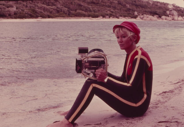 Valerie on a beach holding a camera